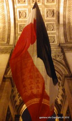 The flag of France flying underneath the Arc de Triomphe. 