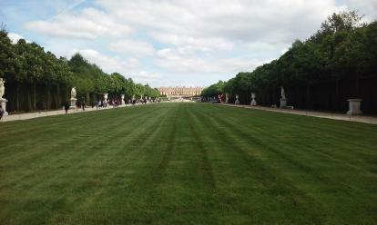 A long grass lawn leading to the Palace of Versailles. Beyond this lawn is the Grand Canal